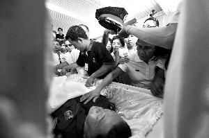 28日，兇手門多薩身著警服躺在棺木里。